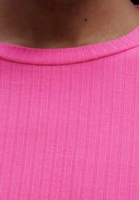 Haut moulant rose côtelé avec un col rond. Le tissu a une texture lisse, et des lignes verticales sont visibles sur l'ensemble du motif.