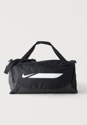 Μαύρη τσάντα Nike duffel με λευκό λογότυπο, διπλές λαβές και ρυθμιζόμενο ιμάντα ώμου σε απλό φωτεινό φόντο.