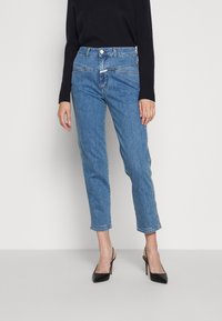 Jeans de mezclilla de color azul claro con cintura alta, piernas ajustadas y un largo recortado. Presentan un cierre delantero con botón y detalles de costura sutiles.