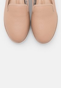 Baskets à enfiler rose pâle avec un motif texturé en écailles. Bout arrondi et semelle blanche discrète. Doublure en tissu doux pour un confort optimal.