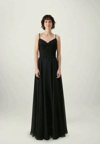 Μαύρο βραδινό φόρεμα με εφαρμοστό ενισχυμένο κορσέ, λεπτές τιράντες και φαρδύ φούστα. Το ύφασμα φαίνεται ελαφρύ με διακριτική γυαλάδα.