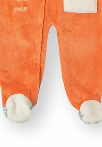 Mono de forro polar naranja con detalles en blanco y pies en forma de patas. Cuenta con un bolsillo delantero y texto bordado que dice "demasiado lindo". Textura suave.