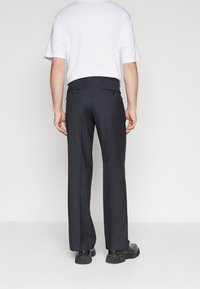 Svarta byxor med skräddarsydd passform, bakfickor och raka ben. Bärs med en enkel vit t-shirt och svarta skor.