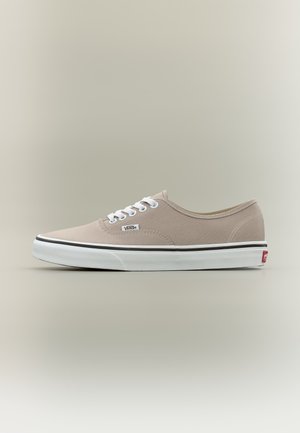 Beige Vans Low-Top-Sneaker mit weißen Schnürsenkeln, weißer Gummisohle und schwarzem Streifendetail vor neutralem Hintergrund.
