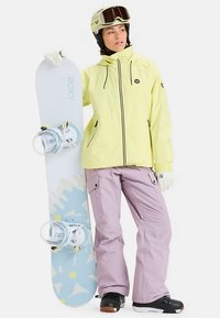 Snowboard met een lichtblauwe onderkant en gele accenten, gecombineerd met een gele jas, lavendelkleurige broek en zwarte snowboardlaarzen.