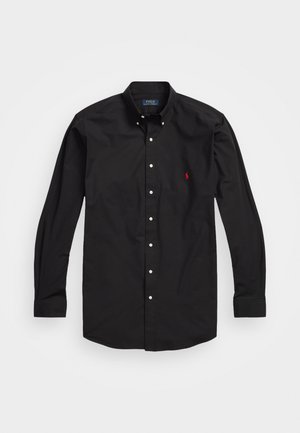 Schwarzes Langarm-Hemd mit Knöpfen aus Baumwolle. Es hat einen klassischen Kragen, weiße Knöpfe und ein kleines rotes gesticktes Logo auf der Brust.