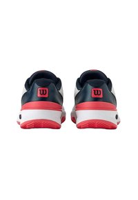 Zapatillas deportivas Wilson con parte superior en azul marino, mediado en blanco y acentos rojos. El diseño incluye una textura suave y un detalle del logo en el talón.