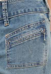 Lyseblå denimjeans med en baklomme med glidelåslukking, forsterkede sømmer og en glatt tekstur.