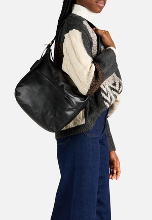 Schwarze Leder-Schultertasche mit einer weichen, strukturierten Oberfläche und verstellbarem Riemen. Kombiniert mit einem stylischen Strickpullover und Jeans.