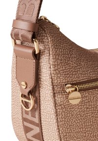 Borsa marrone con motivo, in tessuto testurizzato, con accessori dorati e una larga tracolla regolabile con il nome del brand. Dettaglio della tasca con zip.