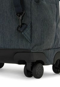 Blå denimmönstrad bagage med ett hållbart, texturerat tyg, svart plastbas och fyra svängbara hjul för enkel manövrerbarhet.