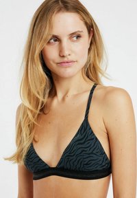 Bralette triangolare nera con motivo a zebra, dotato di spalline sottili e di una fascia elastica nera sotto il seno. Tessuto dalla texture liscia.