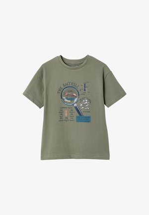 Olive green T-shirt with ant illustrations, a magnifying glass highlighting an ant, text naming common ants, and an ant colony graphic.