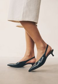 Mustad lakknahast slingback-kontsakingad terava varbaotsaga, madala kassikontsaga ja külgedel lõhikuga. Siledad, läikiva tekstuuriga.