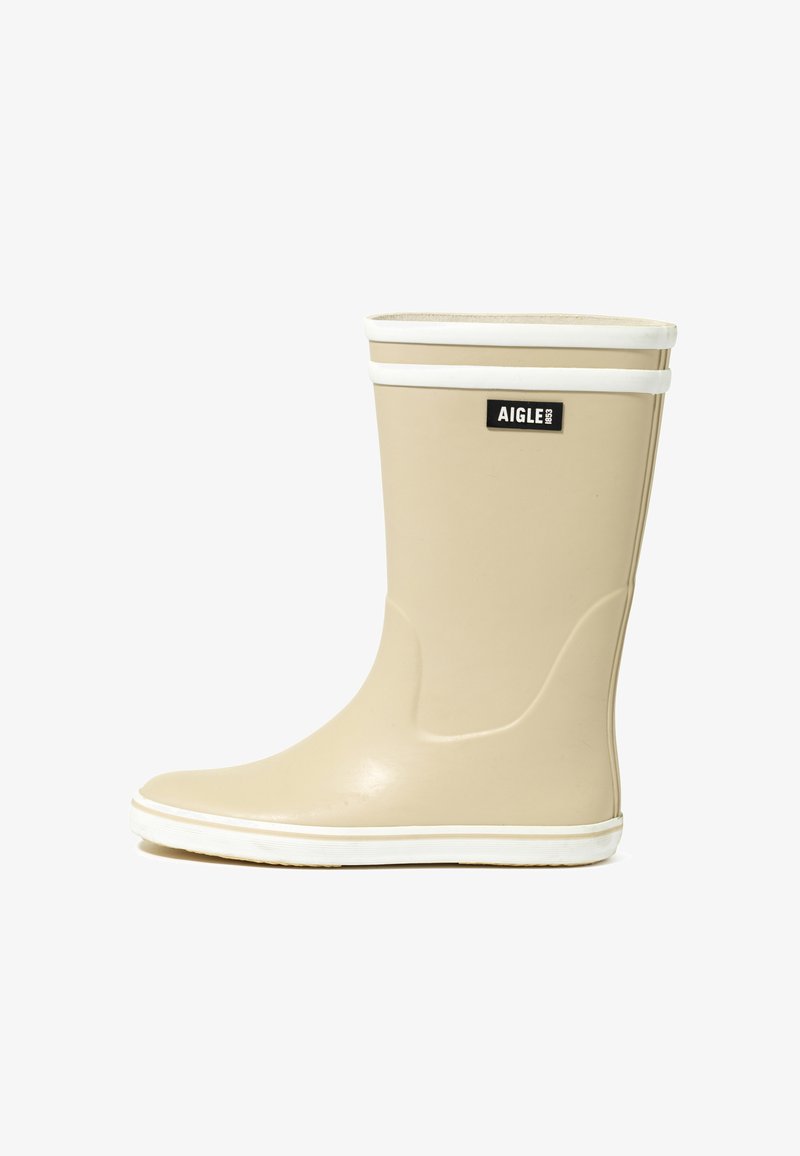 Botte de pluie en caoutchouc beige avec détails blancs, présentant une texture lisse et un bout arrondi. Étiquette logo à l'avant. Conçue pour un usage imperméable.