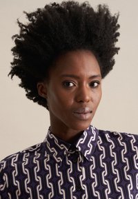 Camicia button-up viola con un motivo a catena bianca ripetuto, dotata di colletto strutturato e tessuto testurizzato.
