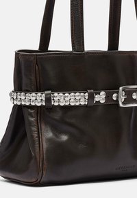 Brązowa skórzana torba na ramię z dwoma solidnymi uchwytami, ozdobiona metalicznym paskiem z kulistymi ćwiekami na środku. Gładka faktura.