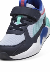Zapatilla deportiva azul marino confeccionada con materiales de malla y sintéticos. Presenta una correa de gancho y bucle, acentos texturizados y una suela blanca estampada.