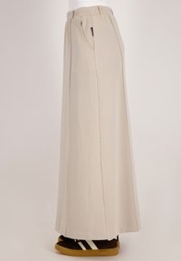 Beige, hoge taille, wijde broek gemaakt van zachte stof, met zijzakken en een gladde textuur. Gestyled met bruine sneakers.