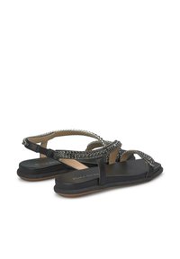 Schwarze Sandale mit dekorativen Akzenten aus Strassriemen, flacher Sohle, offenem Rücken und verstellbarem Knöverschluss. Glatte Textur.