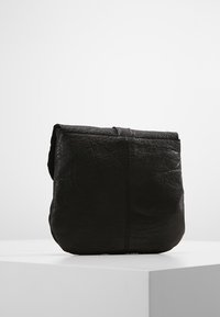 Borsa in pelle nera con finitura testurizzata, caratterizzata da una forma morbida e strutturata e un design minimalista. Chiusura superiore senza ferrature visibili.