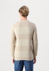 Maglione lavorato a maglia in tonalità beige con righe orizzontali. Presenta un colletto girocollo, polsini a costine e tessuto testurizzato.