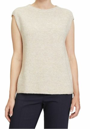 Haut en tricot beige sans manches porté avec un pantalon bleu marine, montré de la nuque aux hanches sur une personne debout.