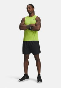 Completo sportivo composto da una canotta senza maniche verde brillante e pantaloni neri. Include un braccialetto nero e scarpe da ginnastica nere con suola bianca.