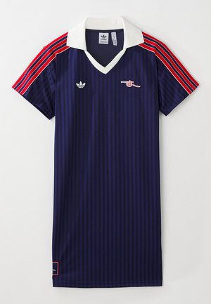 Maglia da calcio blu navy con righe verticali, colletto bianco, maniche a righe rosse e bianche, loghi Adidas e Arsenal, e etichetta sull'orlo.