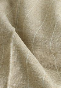 Tessuto intrecciato beige con una superficie testurizzata, caratterizzato da sottili motivi a strisce bianche che scorrono diagonalmente attraverso il materiale.