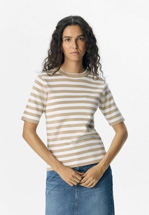 Stribet beige og hvid strikket T-shirt med rund halsudskæring og korte ærmer, parret med en denimnederdel. Stoffet ser blødt og tekstureret ud.