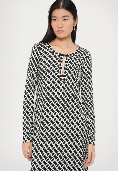 Melns un balts rakstains kleita ar garām piedurknēm, ar noapaļotu kakla izgriezumu un atslēgas cauruma detaļu priekšpusē. Izgatavota no gludas auduma.