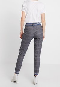 Geruite grijze broek met een slim fit, voorzien van een blauwgestreepte tailleband en ritssluitingen bij de enkels, gemaakt van textuurstof.