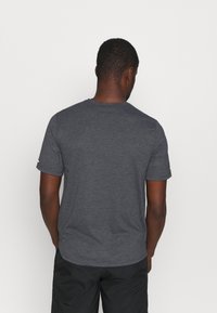 Szary t-shirt z krótkim rękawem, okrągłym dekoltem i gładką fakturą, z minimalnym przeszyciem i metką na lewym rękawie.