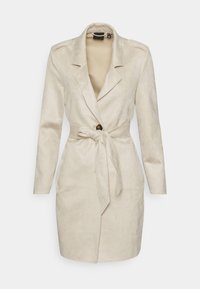 Beżowa zamszowa marynarka z wykładanym kołnierzem, d�ługimi rękawami, zapięciem na jeden guzik oraz przewiązanym paskiem w talii; gładka tekstura.