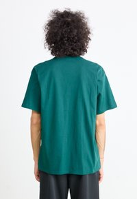 Green cotton t-shirt with short sleeves, round neckline, and straight hem. The fabric appears smooth with no visible patterns or accents.