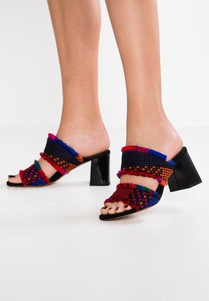 Mules tissés colorés avec une tige en tissu texturé présentant des accents rouges, bleus et violets, et un talon noir épais. Design ouvert à l'avant.