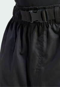 Pantalon taille élastique noire avec une fermeture à boucle en plastique noir réglable à l'avant.
