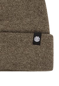 Bruine gebreide beanie met een omgeslagen rand. Beschikt over een zwart label met een wit logo. De stof voelt zacht aan en heeft een gestructureerde textuur zonder patronen.