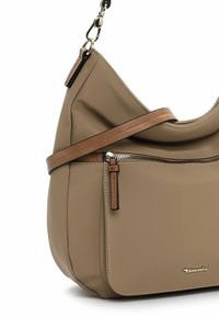 Borsa a spalla sintetica beige con design curvo, dettagli in pelle marrone, una tasca con zip e logo dorato nella parte inferiore.