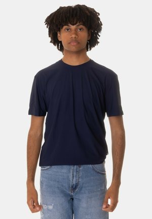 T-shirt a maniche corte color navy con colletto tondo realizzato in tessuto morbido, abbinato a jeans chiari strappati. Design semplice e versatile.