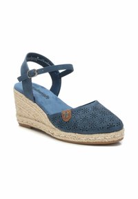 Sandalia de cuña de ante azul con diseño floral perforado, correa de tobillo ajustable y tacón de plataforma envuelto en yute. Interior suave y texturizado.