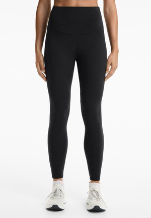 Leggings negre cu talie înaltă, cu o textură netedă, având un design ajustat și fără modele vizibile sau elemente hardware.