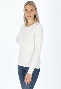 Wit overhemd met lange mouwen, gemaakt van zachte stof, met een ronde halslijn, slim fit en een gladde textuur, gecombineerd met blauwe jeans.