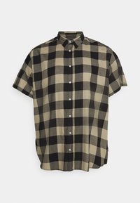 Camisa de manga corta con botones en un patrón de cuadros beige y negro. Hecha de tela ligera con un ajuste relajado y cuello estándar.