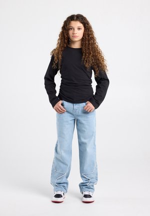Long-sleeve black shirt, light blue baggy jeans with star-shaped stitching, and sneakers with a white base and black accents.