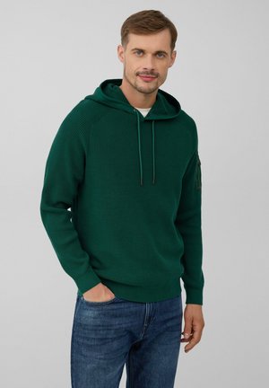 Groen hoodie met een textuur gebreid patroon, verstelbare trekkoorden en geribbelde manchetten, gedragen met blauwe jeans.