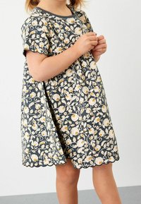 Blumenkleid mit kurzen Ärmeln, grauem Grund, weißem und gelbem Blumenmuster, gewelltem Saum und weichem Baumwollmaterial.