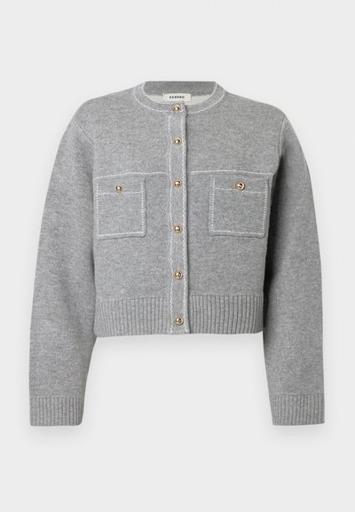 Cardigan corto grigio realizzato in morbido materiale a maglia; presenta bottoni dorati e due taschini sul petto con cuciture a contrasto.