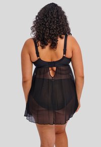 Musta läpinäkyvä yöasu säädettävillä hihnoilla, pyöreä takaleikkaus ja levenevä helma. Kangas näyttää kevyeltä ja läpikuultavalta.